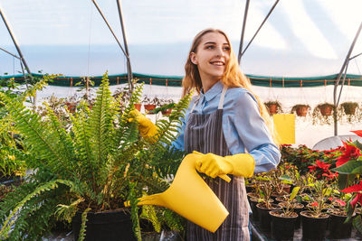 Young woman smiling while standing by plants