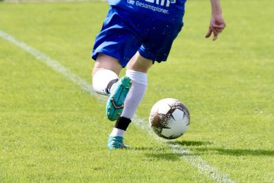 Low section of man playing soccer on field