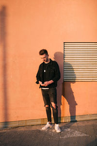 Full length of young man standing against wall