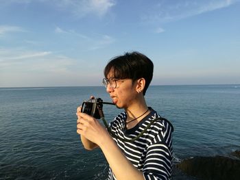 Man photographing at beach against sky