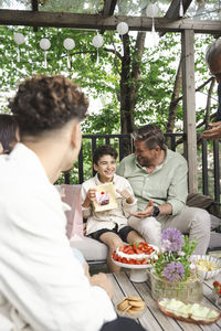 Happy father and son with gift sitting on sofa at patio in back yard