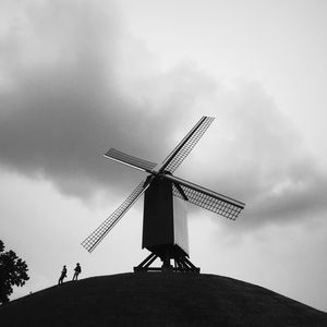 Low angle view of traditional windmill against cloudy sky