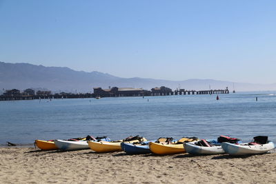 Boats moored on beach against clear sky