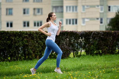 Side view of young woman exercising on field