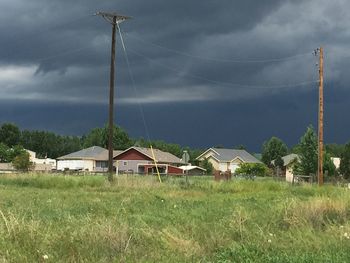 View of houses on grassy field against cloudy sky