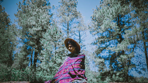 Low angle view of girl standing by tree against sky