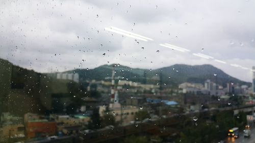 Raindrops on window against sky