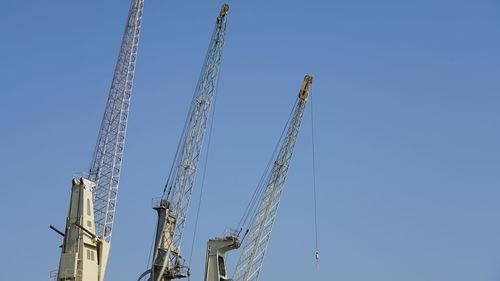 Low angle view of crane against clear blue sky