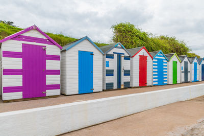 Beach huts by buildings against sky