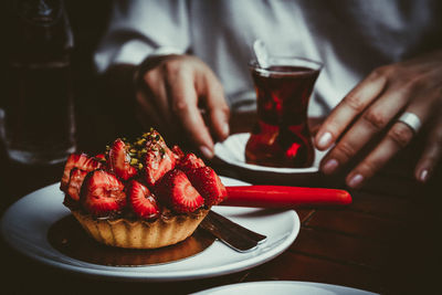 Midsection of man holding ice cream in plate on table