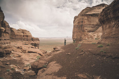 Rear view of a man standing on landscape against clouds