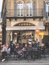 People sitting at restaurant by buildings in city