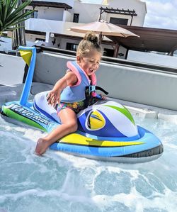 Toddler in jacuzzi on inflatable jet ski. 