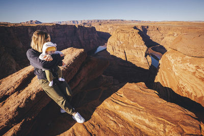 A woman with a child is sitting near horseshoe bend, arizona