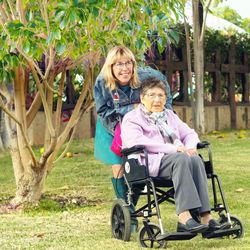 Cheerful daughter caring mother on wheelchair at lawn