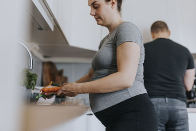 Pregnant woman peeling vegetables in kitchen