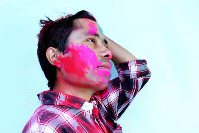 Portrait of young man looking away against gray background