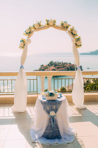 View of white wine in glass on table by sea against sky