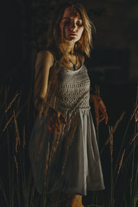 Young woman looking away while standing on field