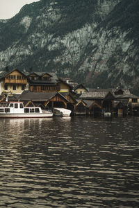 Houses by lake and buildings against mountain