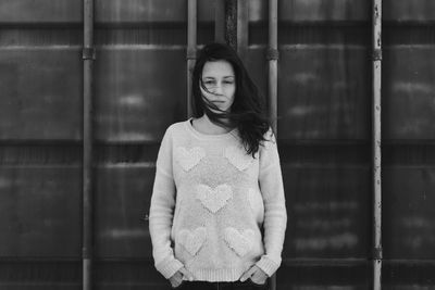 Portrait of woman standing against metallic container