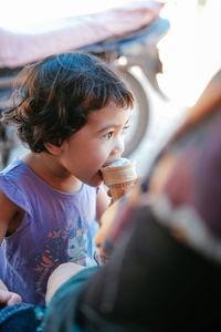 Midsection of mother feeding ice cream to daughter