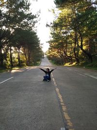 Man sitting on skateboard on road