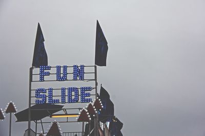 Illuminated neon sign on amusement park at dusk