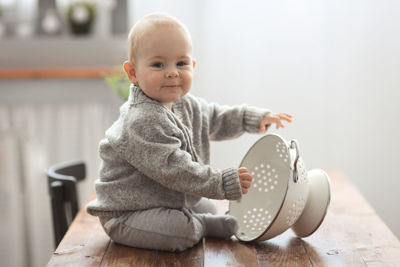 Funny kid in a comfortable sweater playing in a cozy real kitchen, lifestyle and light smoky toning