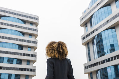 Afro businesswoman standing in front of office building in city