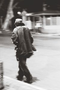 Blurred motion of man walking on road at night