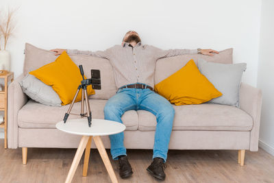 Smiling bearded guy filming video using smartphone on tripod online while