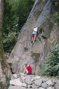 Low angle of women climbing rock in forest