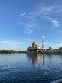 View of temple by lake against sky