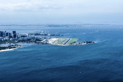 High angle view of sea and city buildings against sky