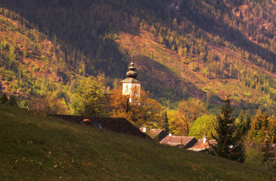 Illuminated building amidst trees and mountains during autumn