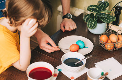 Easter day. father and son painting eggs. family  in a kitchen. preparing, creative homemade decor