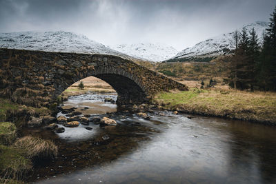 Bridge over river against sky during winter