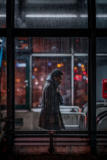 WOMAN LOOKING THROUGH GLASS WINDOW