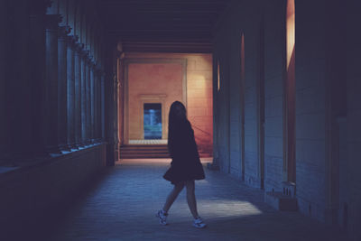 Full length of young woman standing in dark corridor