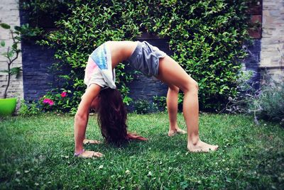 Full length of woman exercising on field in backyard