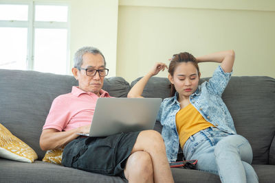 Friends sitting on sofa at home