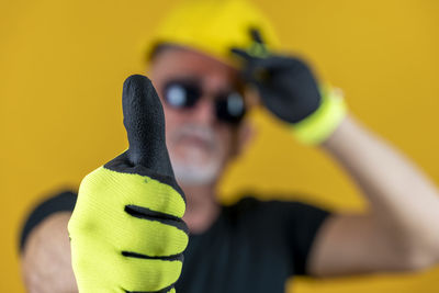 Cropped image of man with camera against yellow background