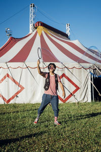 Male artist holding bubble wand while standing in front of circus tent