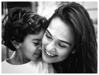 Close-up of smiling boy embracing woman