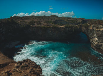 Scenic view of sea and rocks against blue sky