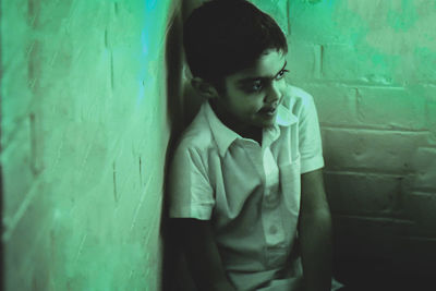 Portrait of a boy looking away against wall