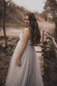 Young woman standing against trees