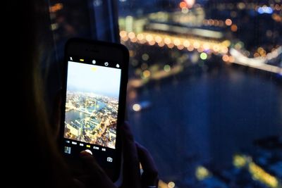 Close-up of hand photographing illuminated smart phone at night