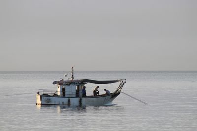 Fishing boat in sea against clear sky